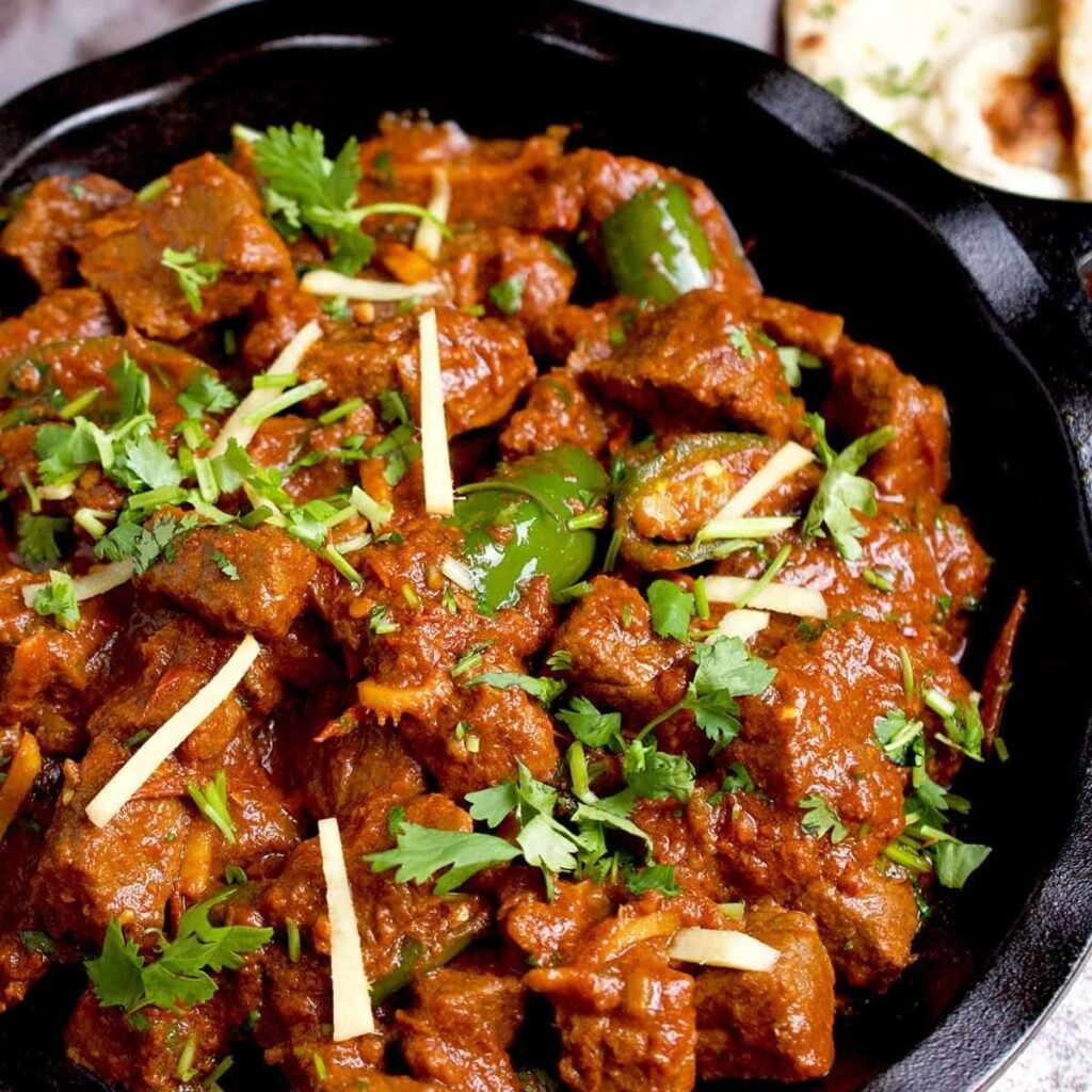 Authentic Pakistani beef karahi with tomato gravy, green chilies, fresh coriander, and ginger garnish.